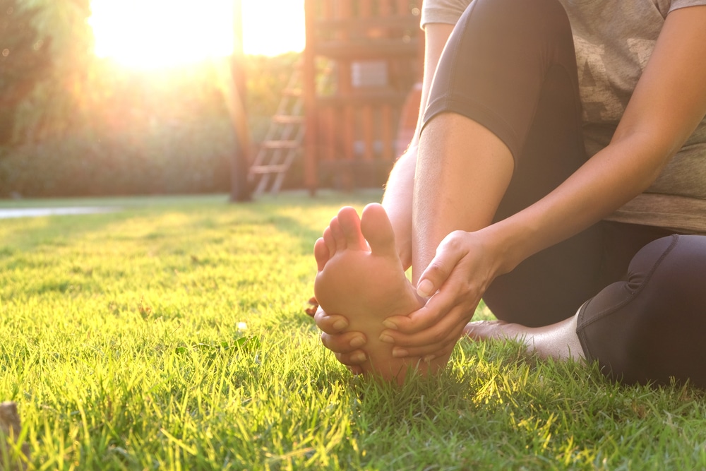 Foot,Pain,.woman,Sitting,On,Grass,Her,Hand,Caught,At Revolutionary Toenail Fungus Treatment in The Woodlands, TX